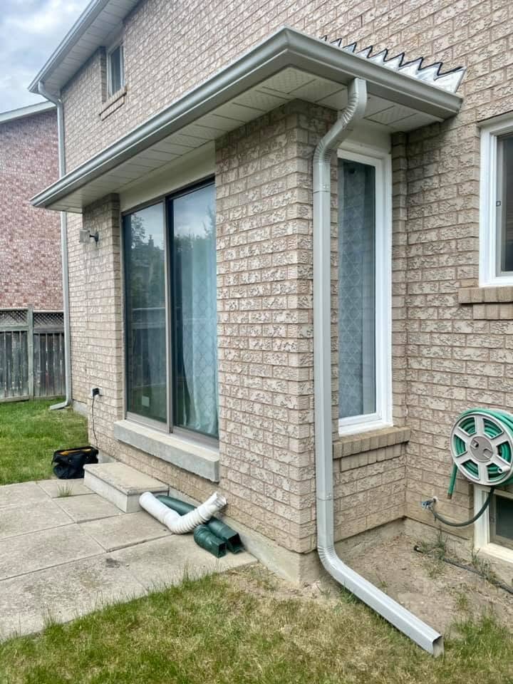 Downspout with a ground-level extension moving water away from a wall.