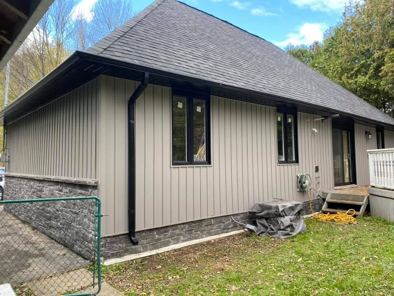 Taupe board-and-batten siding on a home exterior with black window trim.