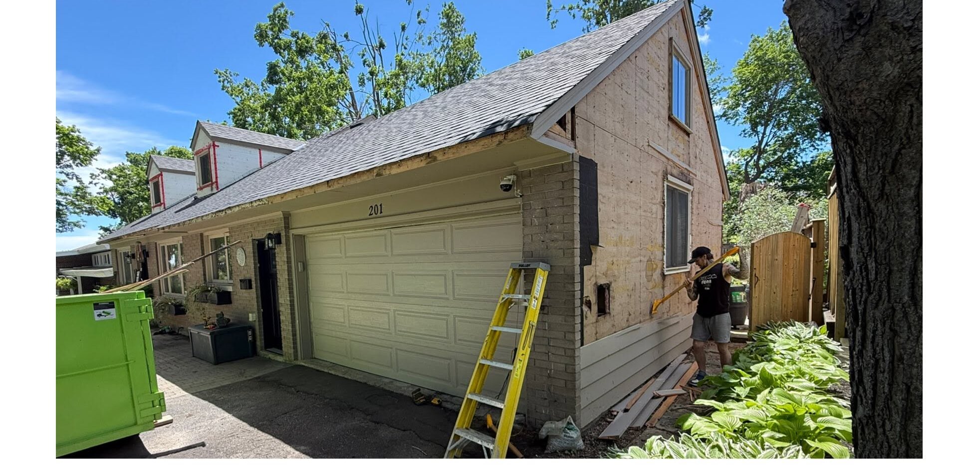 Garage mid-project with siding stripped back and a ladder against the wall.