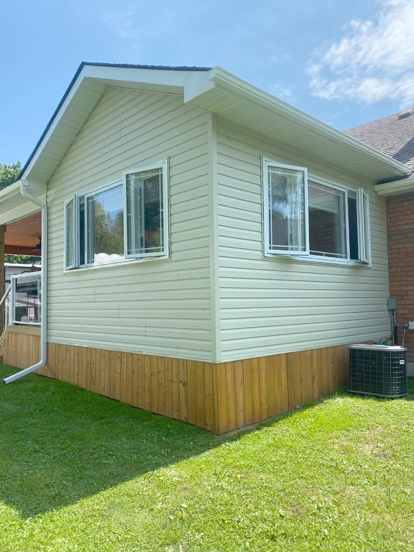 Freshly installed light siding on a small home addition.
