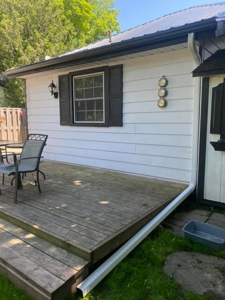 White siding and dark roof-edge trim on a home beside a wooden deck.